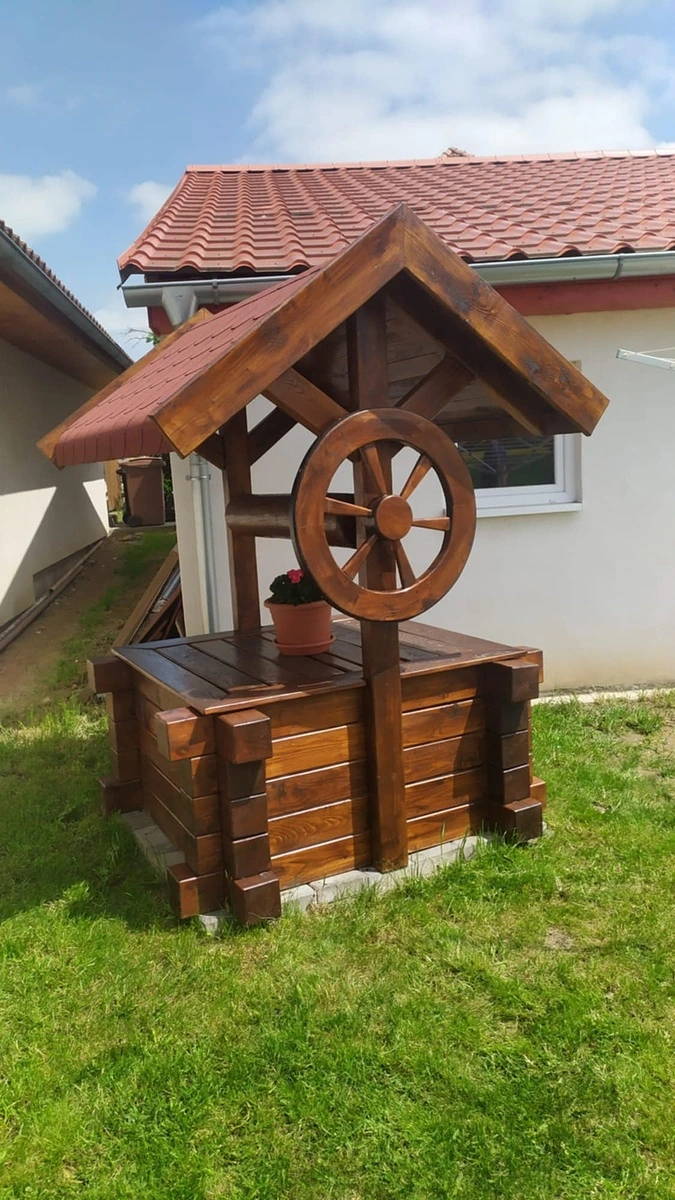 Hotový dřevěný studna s koly na trávníku před domem.