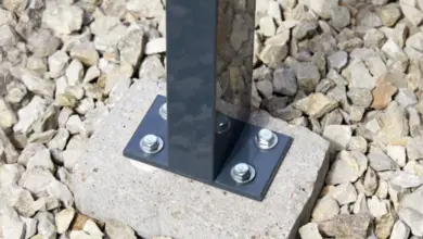 Černý kovový sloup na betonu s šrouby pro terasu.