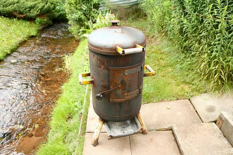 Domácí gril z bojleru postavený vedle potoka.