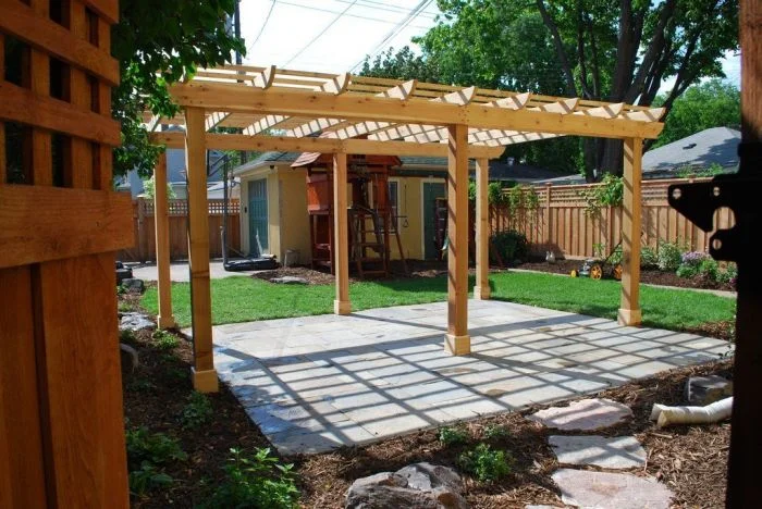 Nová dřevěná pergola na kamenné terase zahradního pozemku.