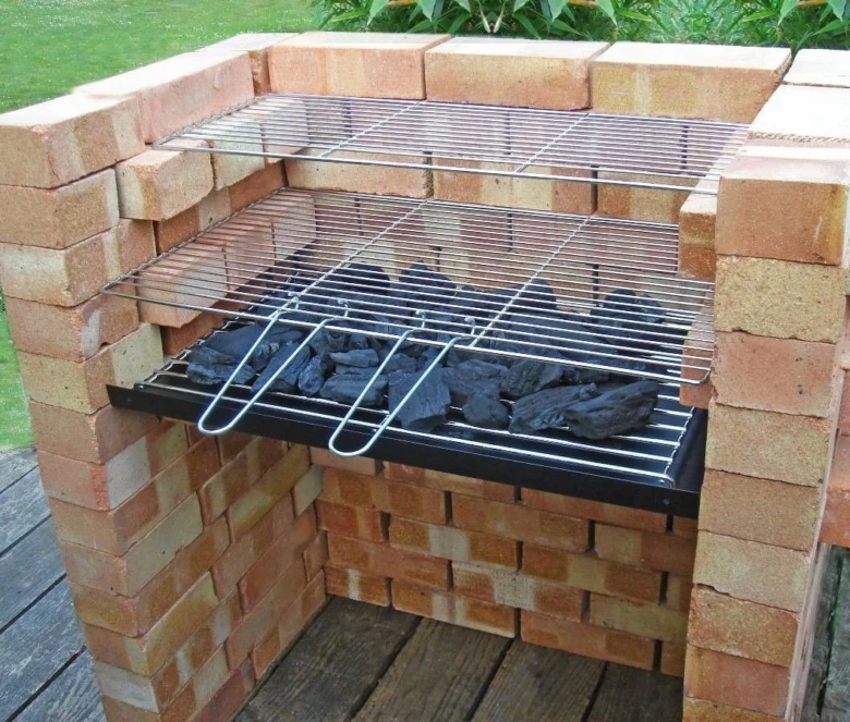 Hotový zahradní gril z cihel s uhlím na roštu.