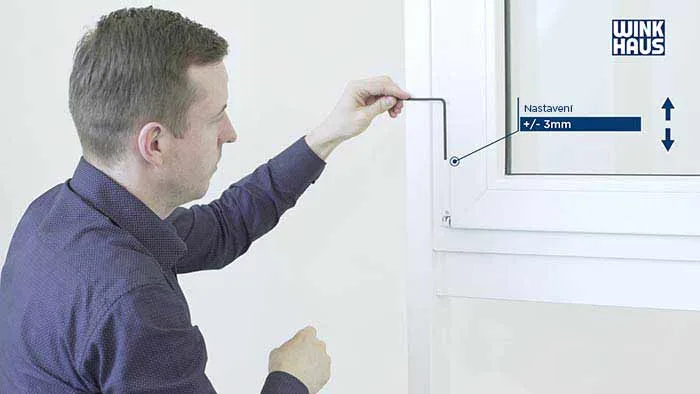 Muž nastavuje plastové okno pomocí nástroje pro přesné seřízení.