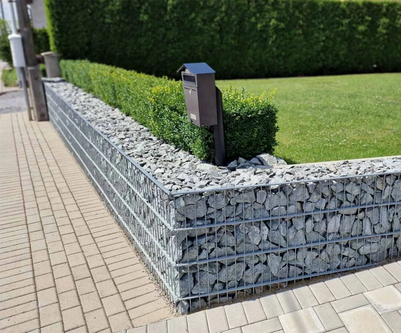 Hotový zahradní zdi ze sítě plné kamenů s poštovní schránkou.