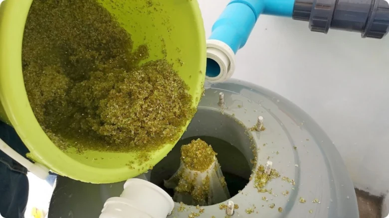 Nalévání písku do bazénové filtrace z žlutého koše.