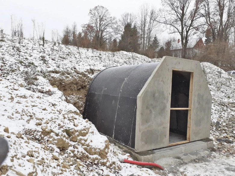 Stavba nadzemního sklepu na sněhové svahu s betonovou konstrukcí.