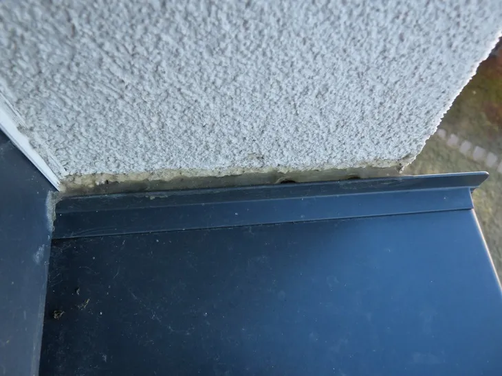 Detail spoje zdiva s okenním parapetem a betonovou základnou.
