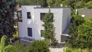 Moderní bílá fasáda domu z kamene v zahradě.