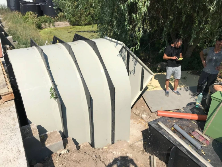Instalace prefabrikovaného sklepa do vykopané jámy s dělníky.