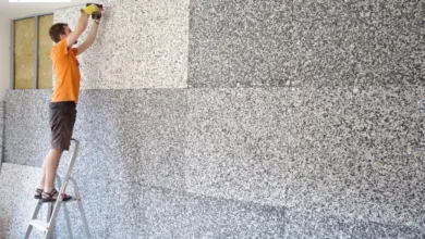 Muž montuje akustické panely na stěnu v interiéru.