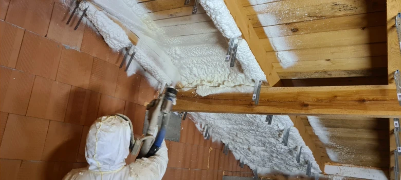 Práce na stříkané izolaci mezi trámy střechy.