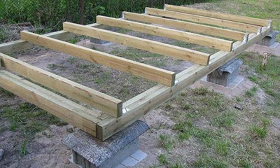 Částečně sestavený dřevěný rám z palet na betonu venku.