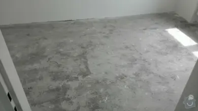Neúpravená betonová podlaha v prázdné místnosti před rekonstrukcí.