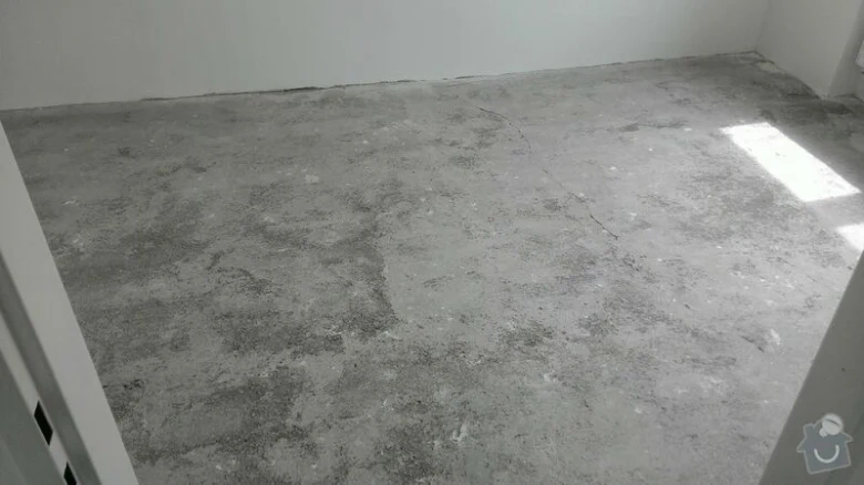 Neúpravená betonová podlaha v prázdné místnosti před rekonstrukcí.
