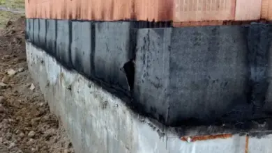 Detailní pohled na zpětný spoj hydroizolace mezi betonem a cihlovou zdí.