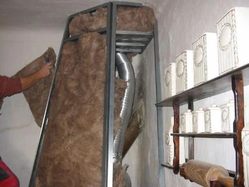 Montáž izolace z minerální vlny do krbového tělesa s výfukovou trubicí.