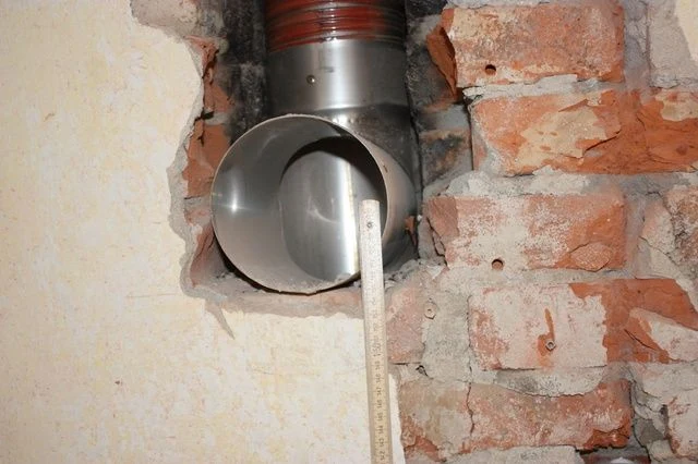 Instalace vložky do komína přes otvor ve zdivu.