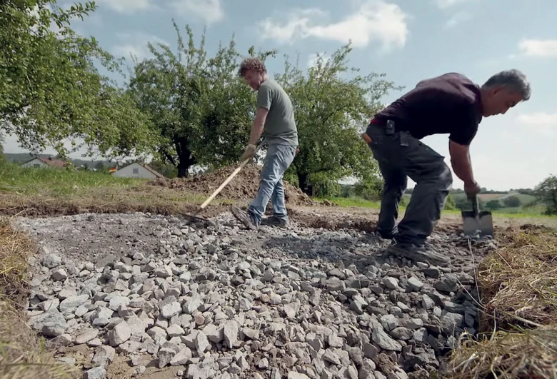Muži připravují štěrkovou vrstvu pro betonáž základů domu.