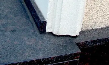 Detail kamenné šambrány u okna s bílým podkladem