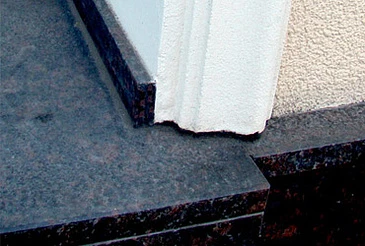 Detail kamenné šambrány u okna s bílým podkladem