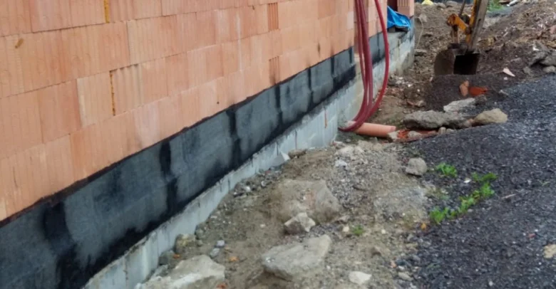Základová stěna s černou hydroizolační fólií před zdivem.