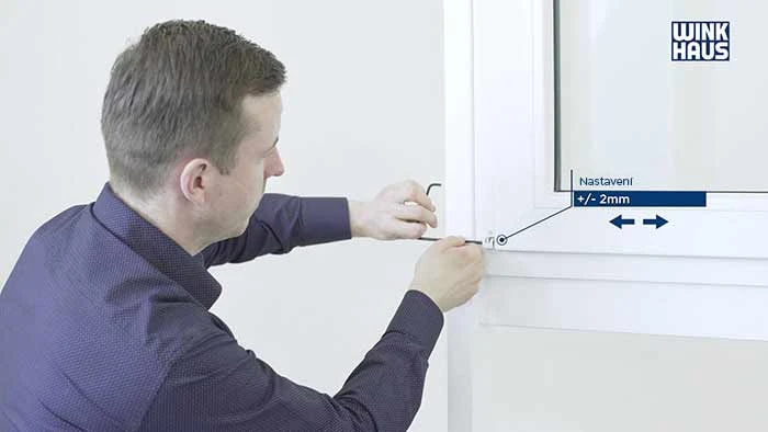 Muž nastavuje přítlak plastového okna pomocí šestihranného klíče.