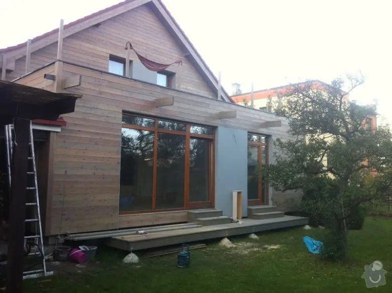 Moderní dřevěná fasáda domu v procesu stavby s velkými okny.