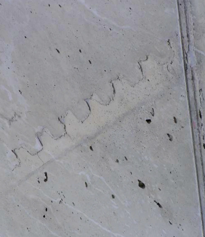 Pohledový beton s viditelnými trhlinami a nerovnostmi povrchu.