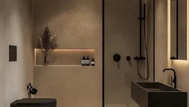 Moderní koupelna s černým toaletem, umyvadlem a sprchou v minimalistickém designu.