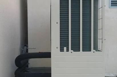 Bílá venkovní jednotka tepelného čerpadla pro ohřev vody.