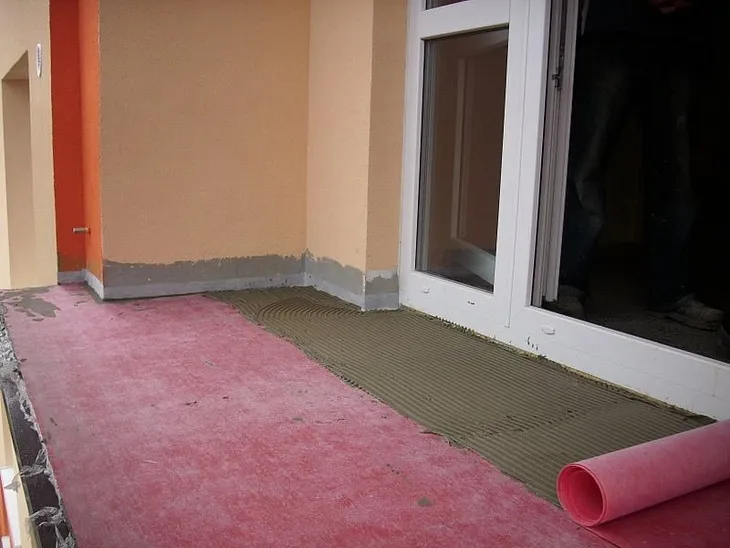 Práce na izolaci balkonu s rozebraným podlahovým krytem.