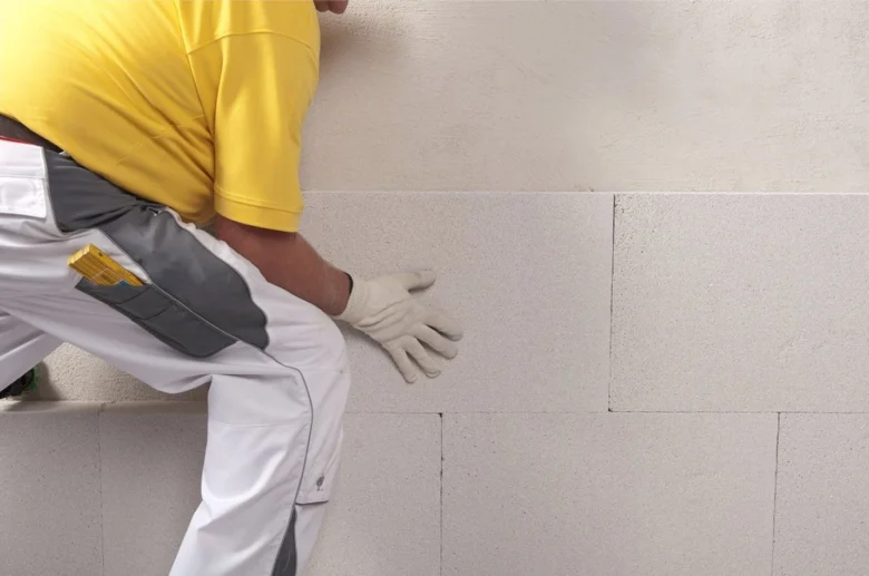 Stavebník lepi panel z expandovaného polystyrénu na stěnu.