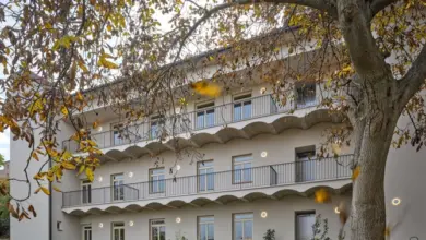 Bílá budova s balkony a okny v podzimním prostředí.