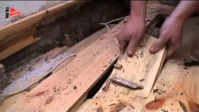Ruční práce s dřevěnými prkny na hlinitém podkladu.