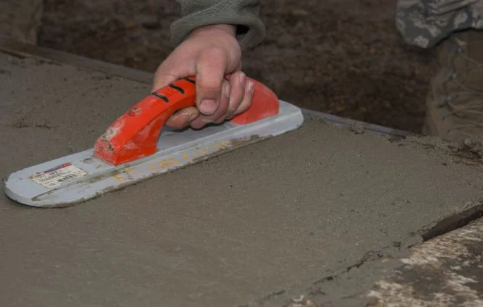 Ruční hladidlo vyrovnává čerstvý beton pro nadzemní sklad.
