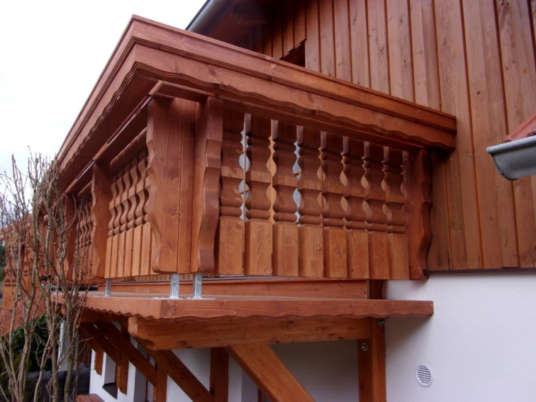 Dřevěné zábradlí na balkóně s ozdobnými sloupky.