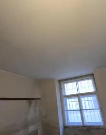 Přestavba starého sklepa s odhalenými zdi a oknem.