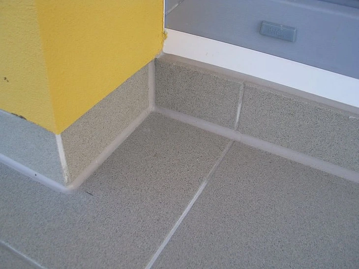 Detail hydroizolace balkonu v rohu s dlažbou a těsnicí hmotou.