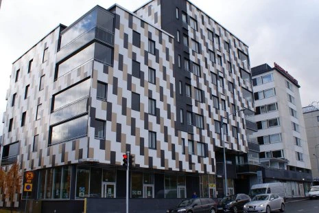 Moderní fasáda domu s geometrickým vzorem z barevných panelů.