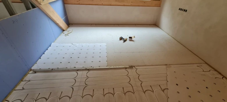 Instalace podlahového topení s izolačními panely v rekonstruované místnosti.