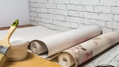 Rolek tapety s květinovým vzorem a nářadí na malování.