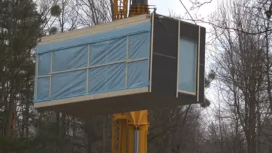 Žlutý kran zvedá modulový dům v přírodě