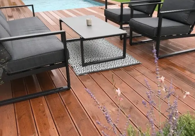 Moderní dřevěná terasa s bazénem a venkovním nábytkem.