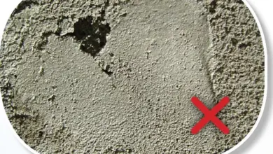 Příprava omítky na opravu poškozené zdi s červeným křížkem.