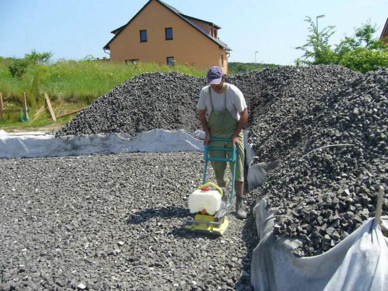 Muž tluče štěrkovou podloží pro bazén ztraceným bedněním.