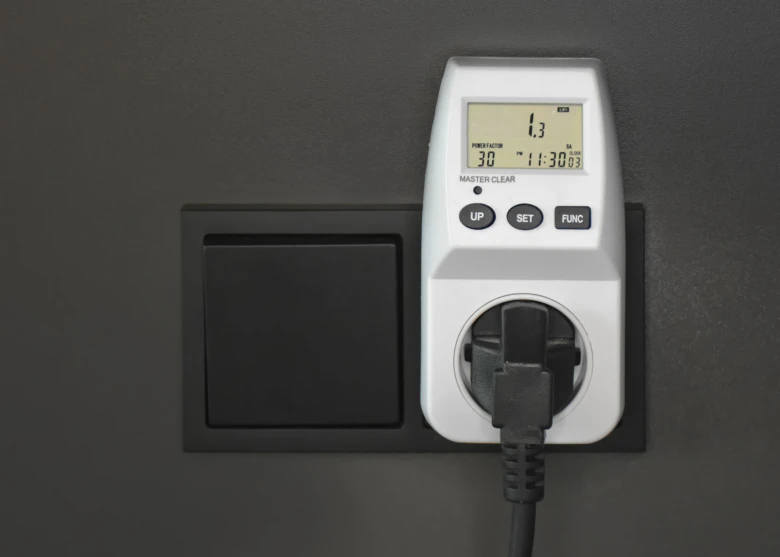 Digitální měnič spotřeby energie připojený do zásuvky s displejem ukazující aktuální hodnoty.