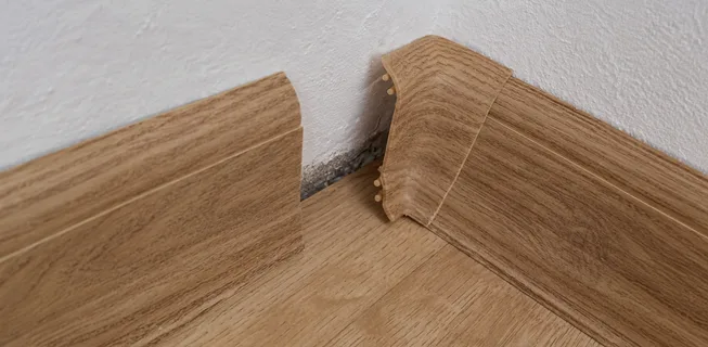 Poškozený roh vinylové podlahy s odlepeným lepidlem.