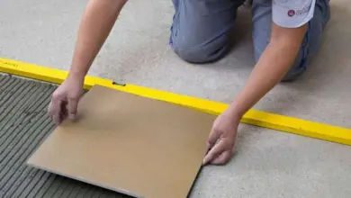 Muž leží dlažbu na podlahu v koupelně.