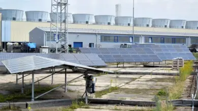 Fotovoltaické panely na střeše s viditelným sklonem u průmyslové budovy.