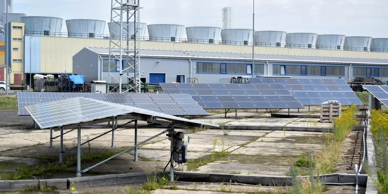 Fotovoltaické panely na střeše s viditelným sklonem u průmyslové budovy.