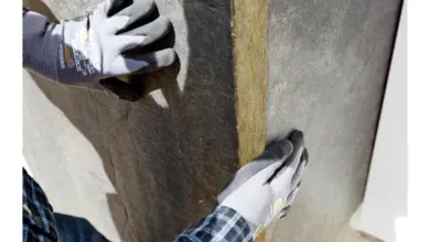 Ruce v rukavicích přitiskují desku z expandovaného polystyrenu ke stěně.